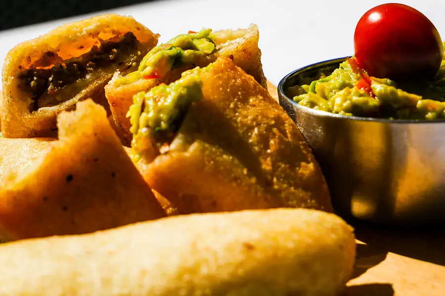 Gros plan d'empanadas coupées, garnies de guacamole